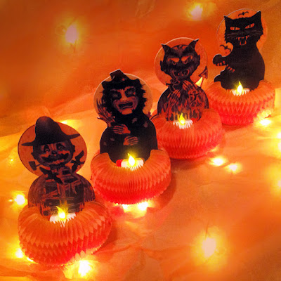 Scarecrow, witch, devil, and black cat hold little battery-operated tealights in this holiday display by product-artist Bindlegrim.