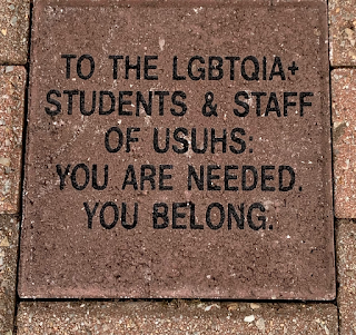 A brick with text that says: "To the LGBTQIA+ students & staff of USUHS: You are needed. You belong”