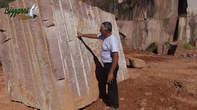 Bizzarri, da Bizzarri Pedras, observando um bloco de pedra de granito vermelho e imaginando cortar a pedra para mesa de pedra, banco de pedra e pedra para jardim.