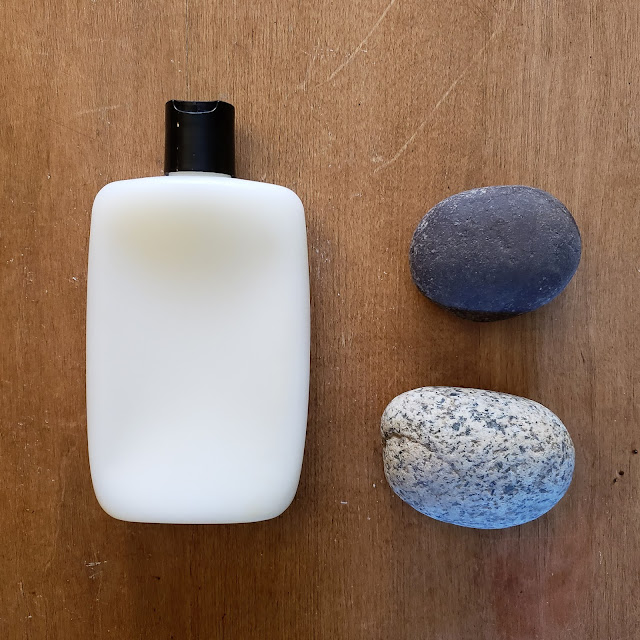 Conditioner bottle laying on a table beside two rocks