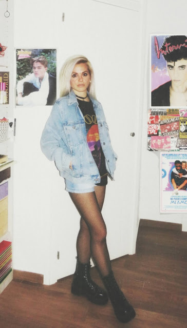 Estilo grunge con camiseta negra ancha con imagen del grupo The Doors, pantalón corto, medias de red pequeña, botas estilo militar y cazadora vaquera