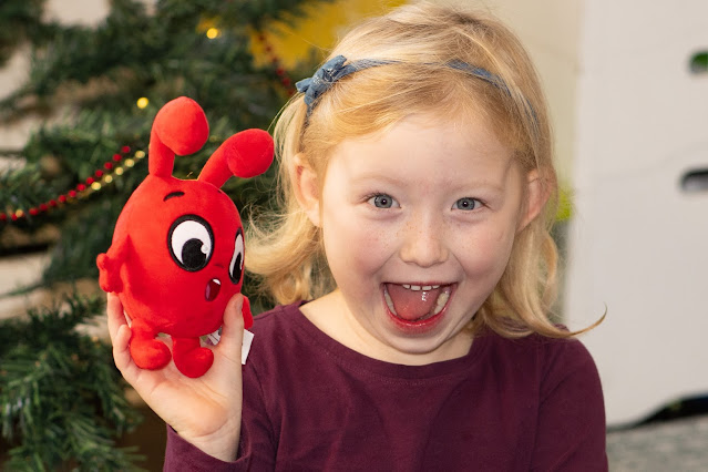 a young girl holding a red Morphle plush toy