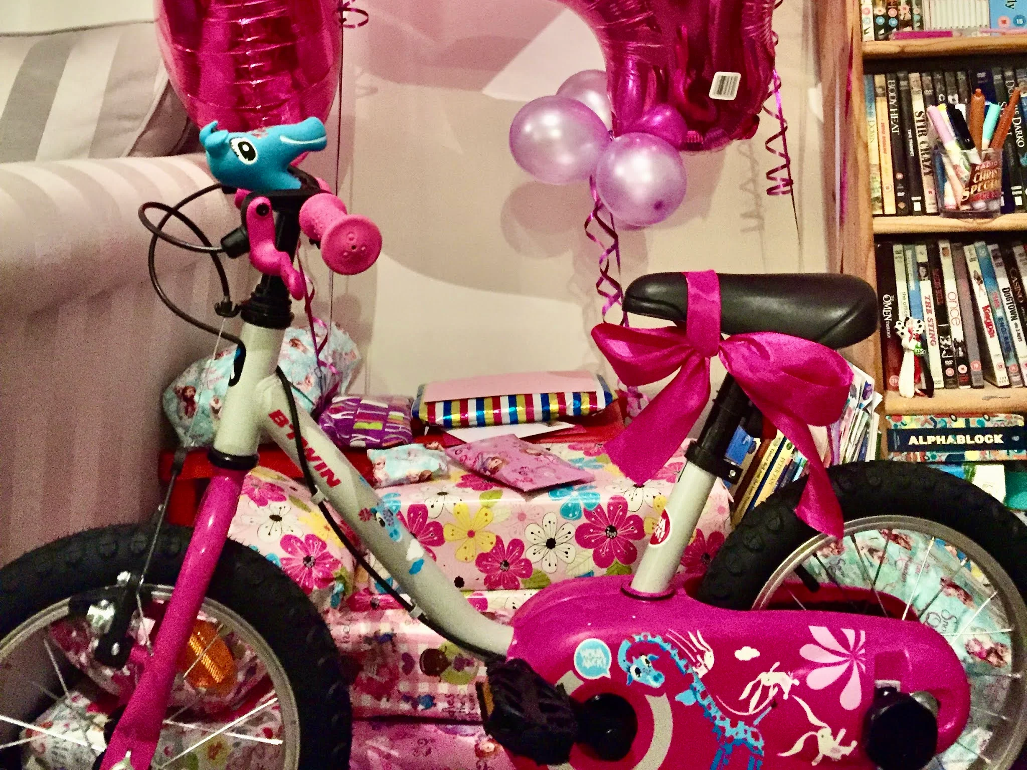 a pile of presents and balloons for a 4th birthday with a bike at the front