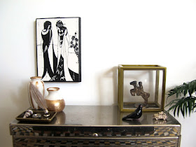 Art deco style modern miniature silver sideboard with a selection of white, black and gold-coloured items displayed on it.