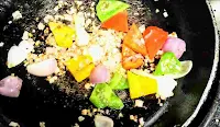 Stir frying onion capsicum red yellow bell peppers for chilli chicken gravy