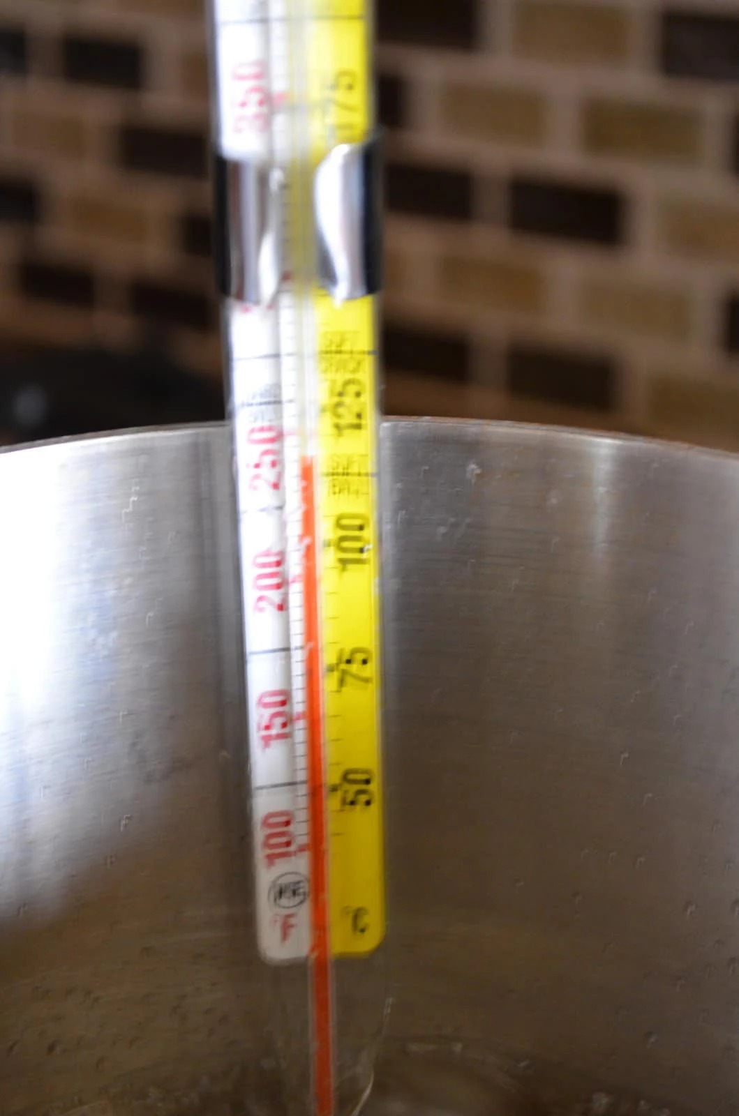 Candy Thermometer at 250 degrees attached to the side of pan in boiling sugar.