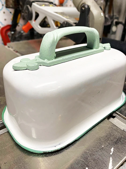 enamelware container with a green handle