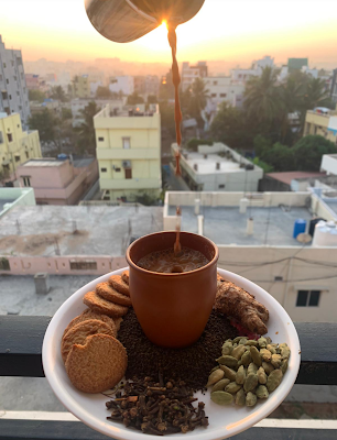 A steaming cup of chai on a railing with a city backdrop behind it