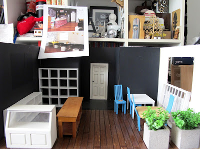 Modern dolls' house miniature cafe interior, empty apart from several shop fittings, tables and chairs.