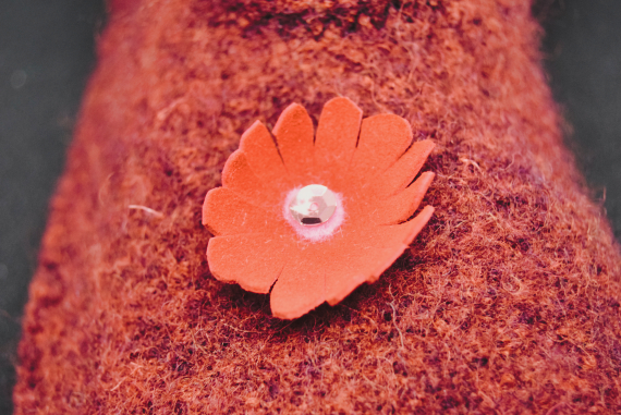 Kuvassa on punainen tossu, jossa on punainen kukka nahasta.
