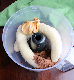 food processor bowl with frozen bananas, peanut butter and cocoa powder for nice cream