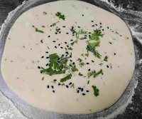 Kulcha dough topped with coriander leaves and Nigella seeds