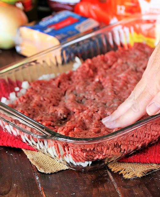Pressing Ground Beef in Pan to Make Easy Cheeseburger Sliders Image