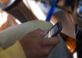 A driver texting while driving. A driver texting while driving.