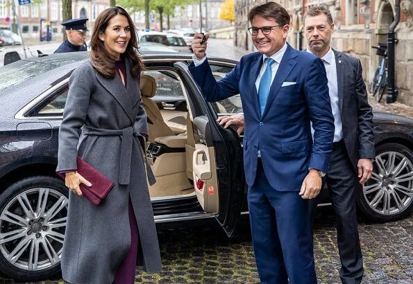 At the award ceremony, Crown Princess Mary wore a burgundy silk mock neck belted top and trousers, and grey cashmere wool long coat