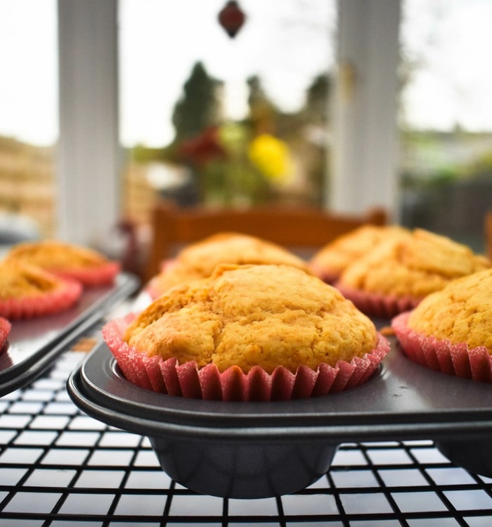 Lemon muffins in a muffin tray sitting on a baking rack