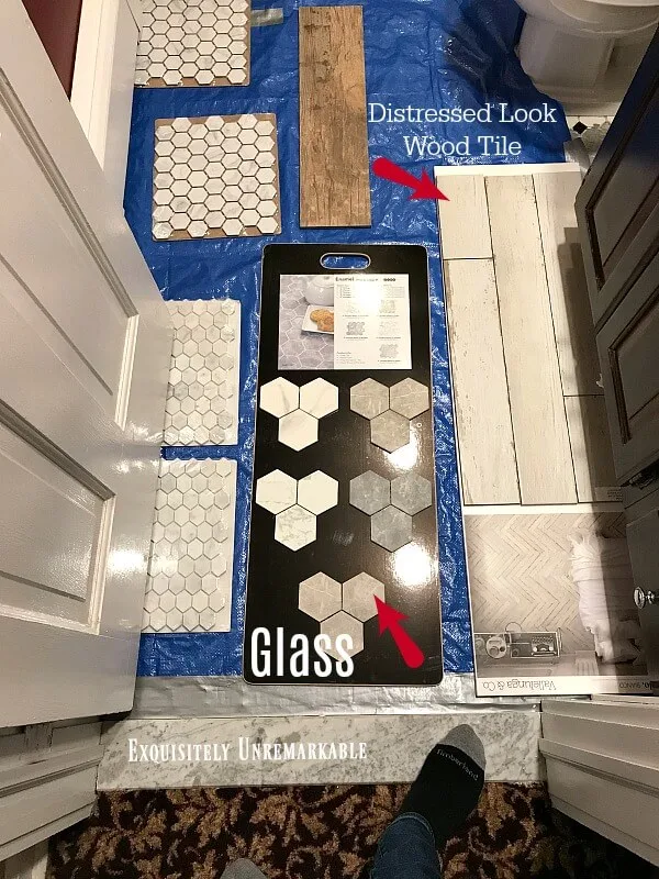 glass and wood tile flooring choices laid out on bathroom floor for comparison