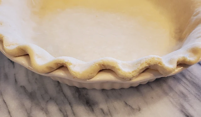 pie crust in pie plate on marble countertop