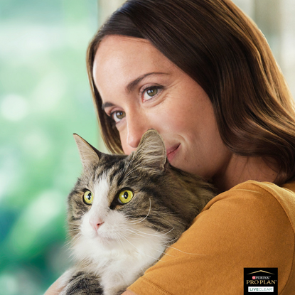 Brunette woman holding long-haired grey-and-white cat
