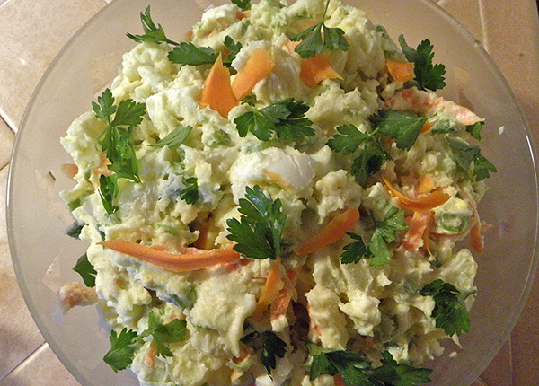 Serving bowl of potato salad with parsley garnish