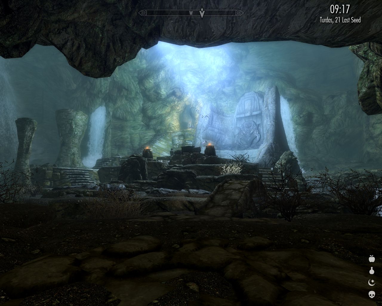 large cavern with bluish light coming from somewhere higher, low staircases leading to a large stone platform