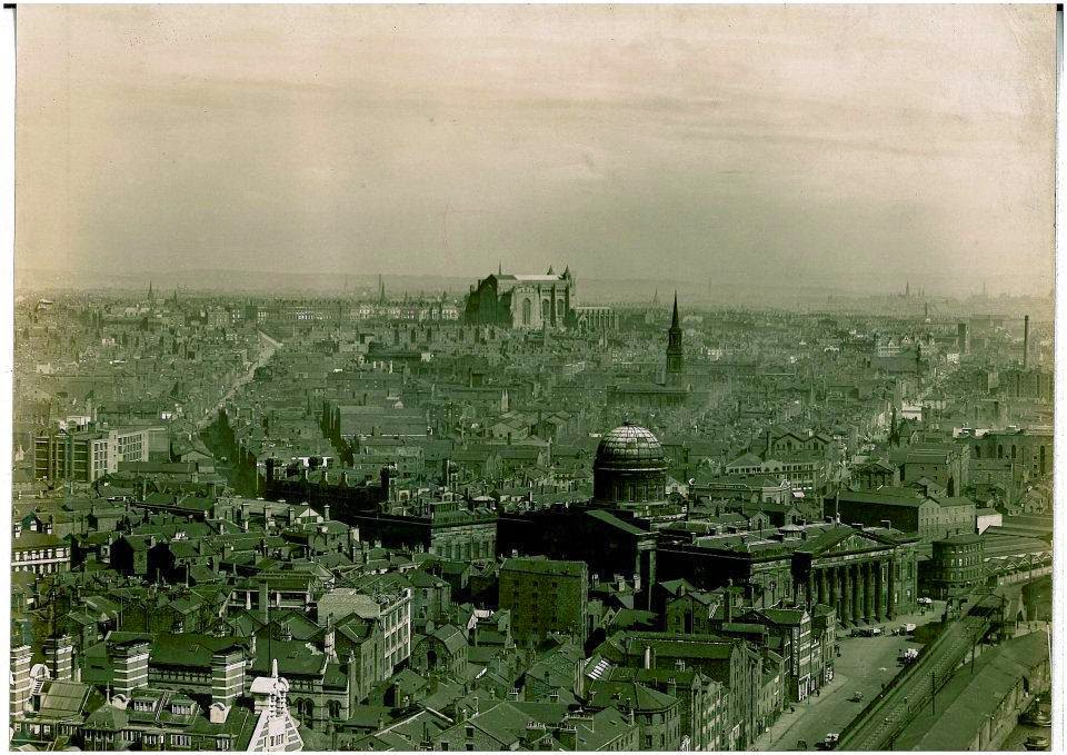 An aerial photograph taken from the central area of the docks. In the distance the Anglican Cathedral is under construction. In the foreground is the now-demolished Customs House. The White Star Lines headquarters, Albion House, is just visible bottom left.