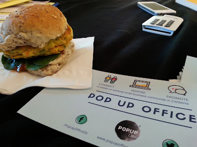 A vegeburger on a napkin next to a flier for The Pop Up Office.