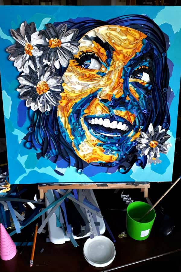 paper portrait of smiling woman on easel with paper art supplies