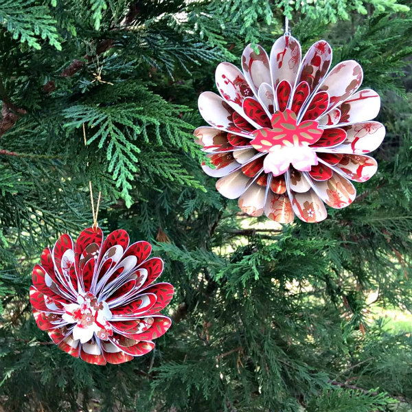 two red, gold, and white curved paper ornaments hanging on evergreen tree