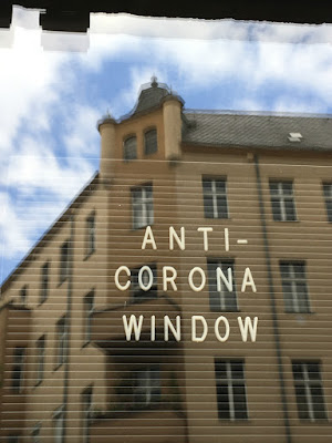 Haus in Spiegelung, Fensteraufschrift ANTI-CORONA WINDOW