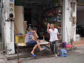 man posing for photo in front of a small convenience store