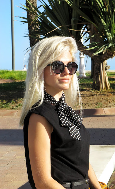 Alejandra Colomera con camiseta negra, pantalón formal negro, lazo en el cuello negro con lunares blancos y complementos mostaza