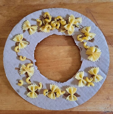 Macaroni wreath in progress: dried macaroni noodles glued to a cardboard circle