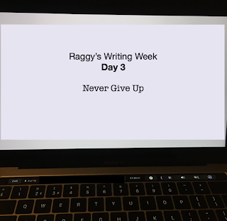 Laptop screen with text 'Raggy's Writing Week Day 3: Never Give Up'