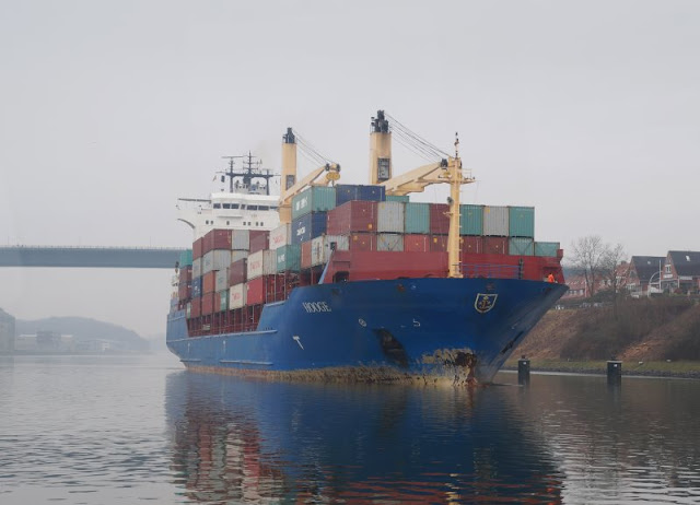 7 Lieblingsplätze zum Schiffe gucken in Kiel. Ein großer Containerfrachter fährt unter der Holtenauer Hochbrücke durch.