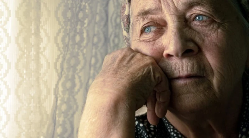 imagem de uma senhora idosa olhando pela janela