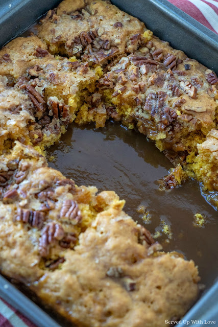 Pumpkin cobbler recipe fresh out of the oven with a couple slices missing with a delicious sauce on the bottom