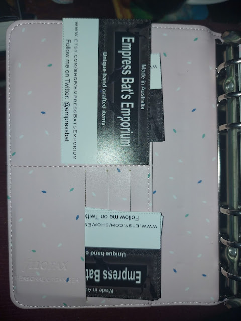 front of a Filofax ring binder, pink fabric with credit card slots, in the slots are business cards