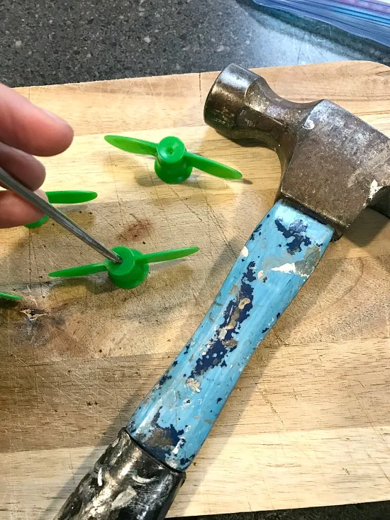 hammering a nail through applesauce tops