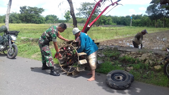 Babinsa Serda Suparman membantu memasang roda traktor guna mengolah lahan 