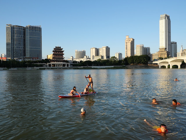people swimming and boating in the Yong River with the Changyou Pavilion in the distance