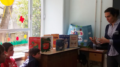 A animadora apresentando os livros aos alunos junto da janela da sala.