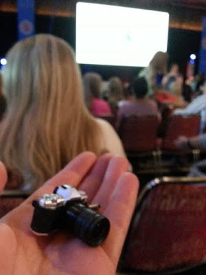 Miniature camera displayed on an open hand in a conference hall.