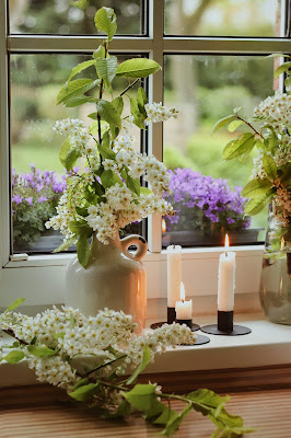 Velas encendidas junto a una ventana y flores