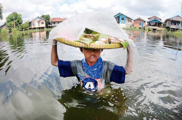 Seorang Bocah Menerobos Banjir demi Berjualan