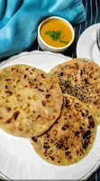 Serving three pieces of onion kulcha, dal 8n background