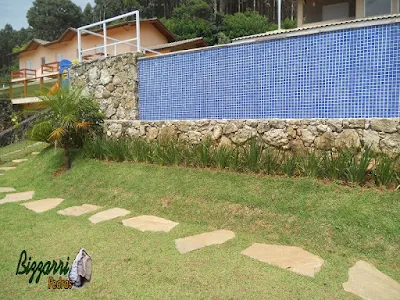 Caminho no jardim com pedra cacão de Carranca com junta de grama com a execução do paisagismo em casa em condomínio em Piracaia-SP.
