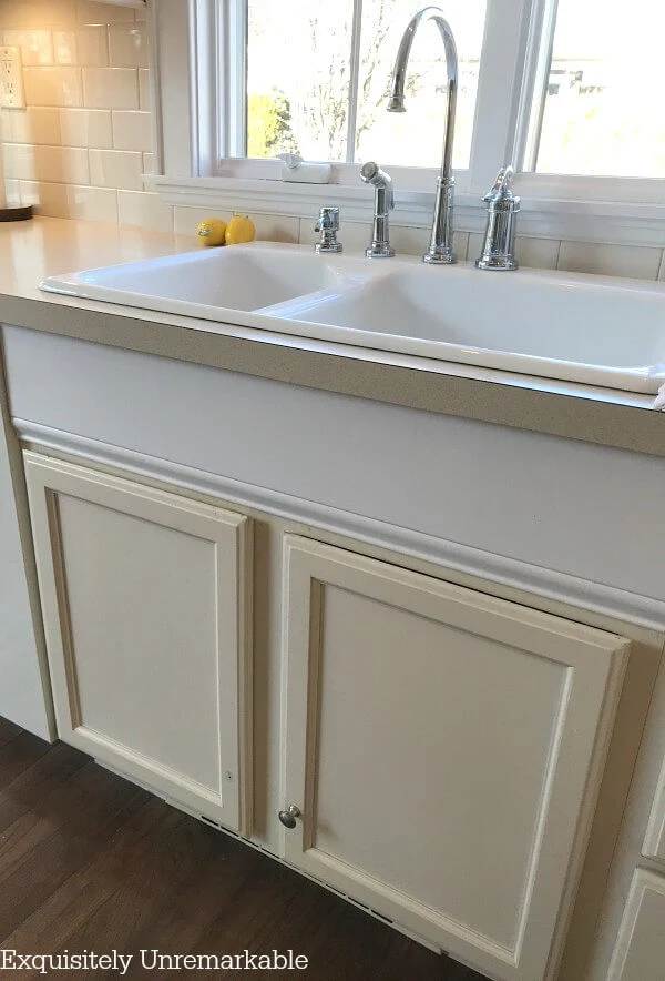 Bisque colored sink base cabinets under a white double sink