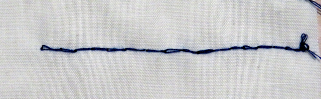 Punto atrás con hilo azul sobre tela blanca por el derecho