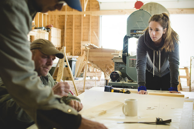 a group of people at work building a wooden boat